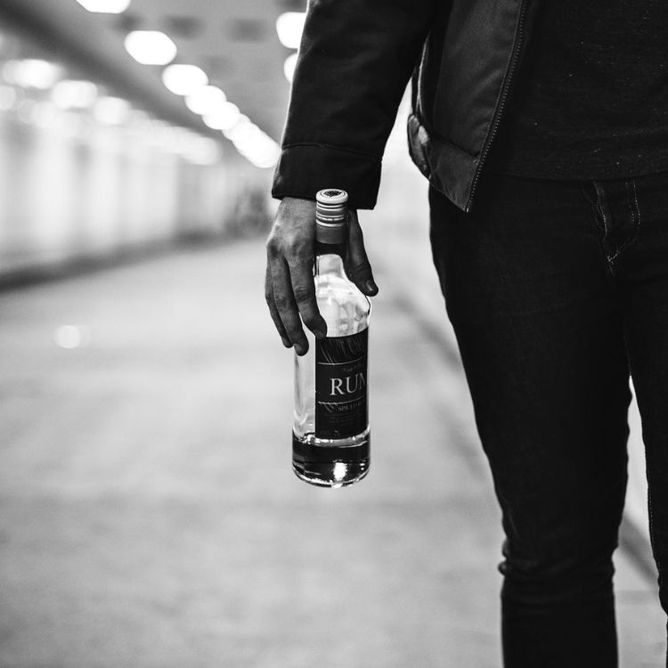 chàng trai cầm chai rượu bước đi