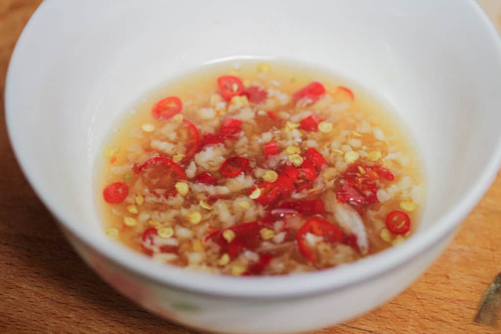 A plate of grilled eggplant segments with scallions and chilis
