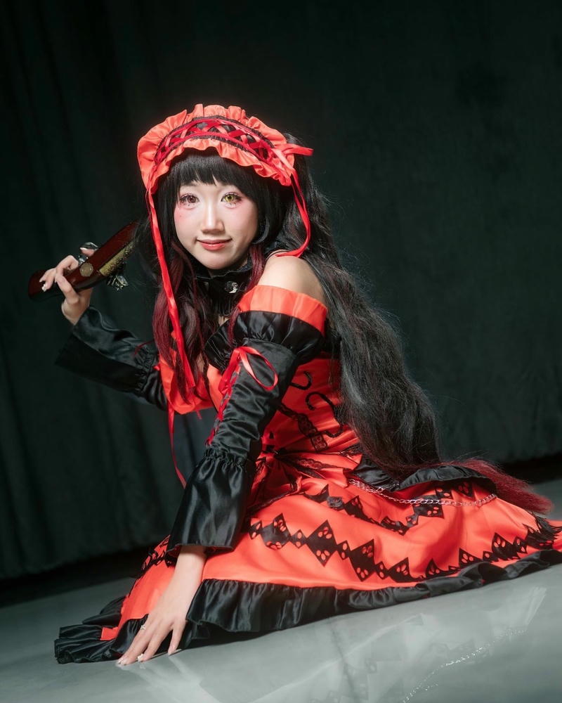 Cosplayer nữ anime váy đỏ đen ngồi tạo dáng bí ẩn