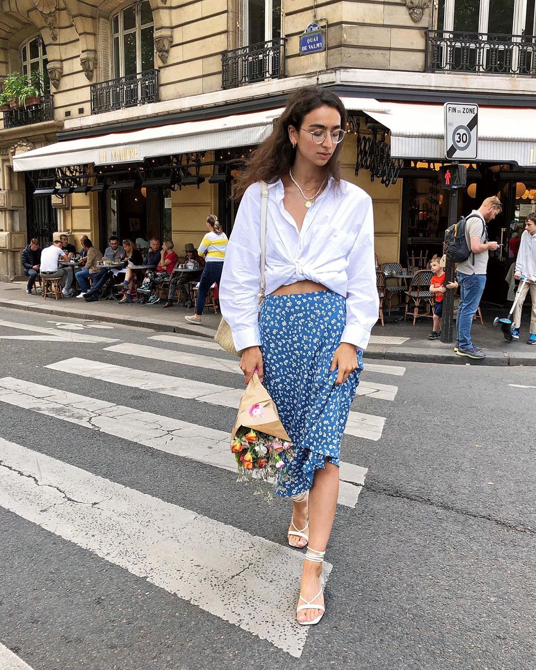 Áo sơ mi trắng phom rộng phối cùng chân váy hoa nhí màu xanh da trời và giày sandals dây mảnh