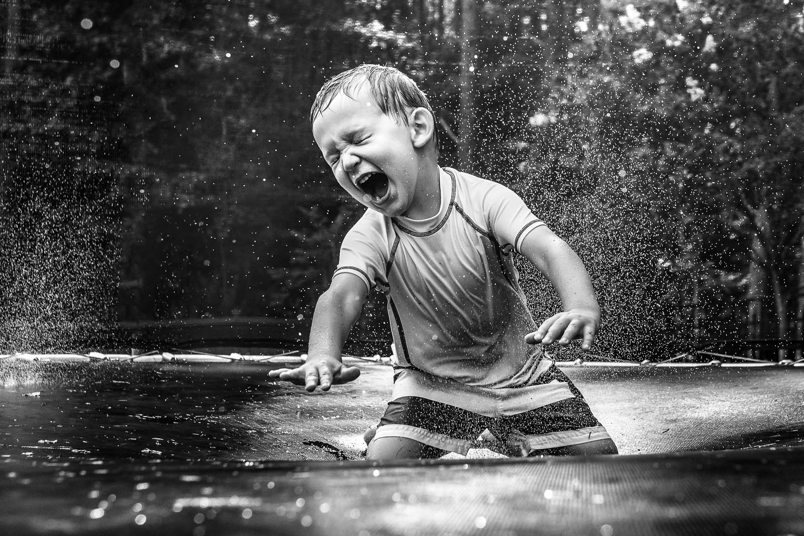 black and white picture of kid getting wet on a trampoline by Susan Grimes