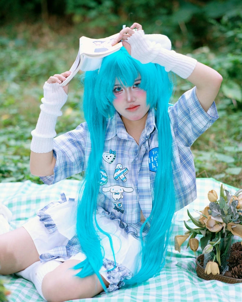 Gái xinh cosplay miku tóc xanh ngồi trên cỏ xanh